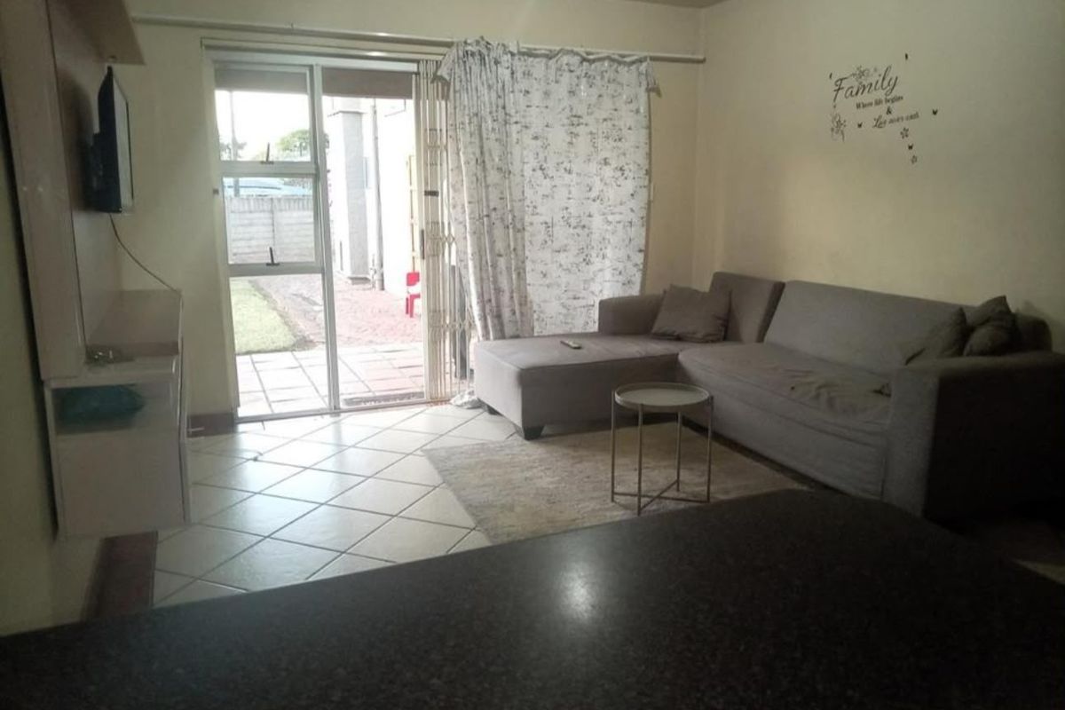 A living room featuring tiled flooring and a sliding glass door providing access to an outdoor patio area.