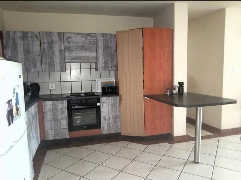 A functional kitchen featuring built-in cabinetry, a tiled backsplash, integrated oven and hob, and a breakfast bar with a metal support leg.