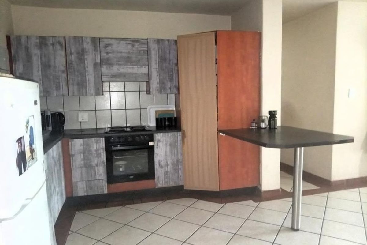 A functional kitchen featuring built-in cabinetry, a tiled backsplash, integrated oven and hob, and a breakfast bar with a metal support leg.