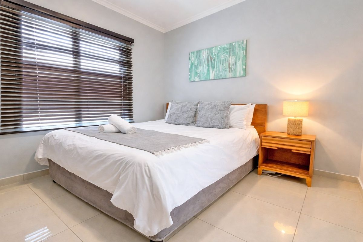 A well-maintained bedroom featuring neutral tiled flooring, coved ceilings, and dark venetian blinds providing adjustable natural light control.