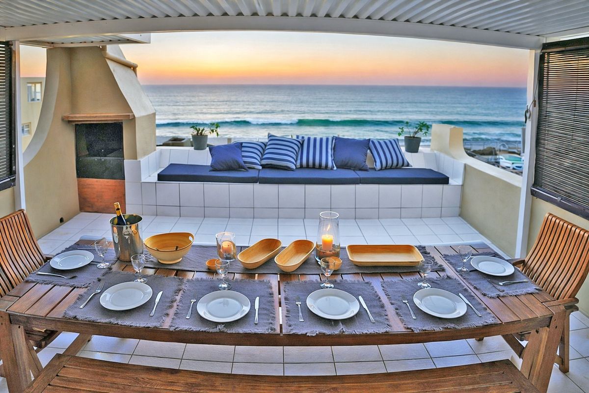 Covered balcony featuring a built-in braai, tiled flooring, and integrated bench seating, offering panoramic ocean views.