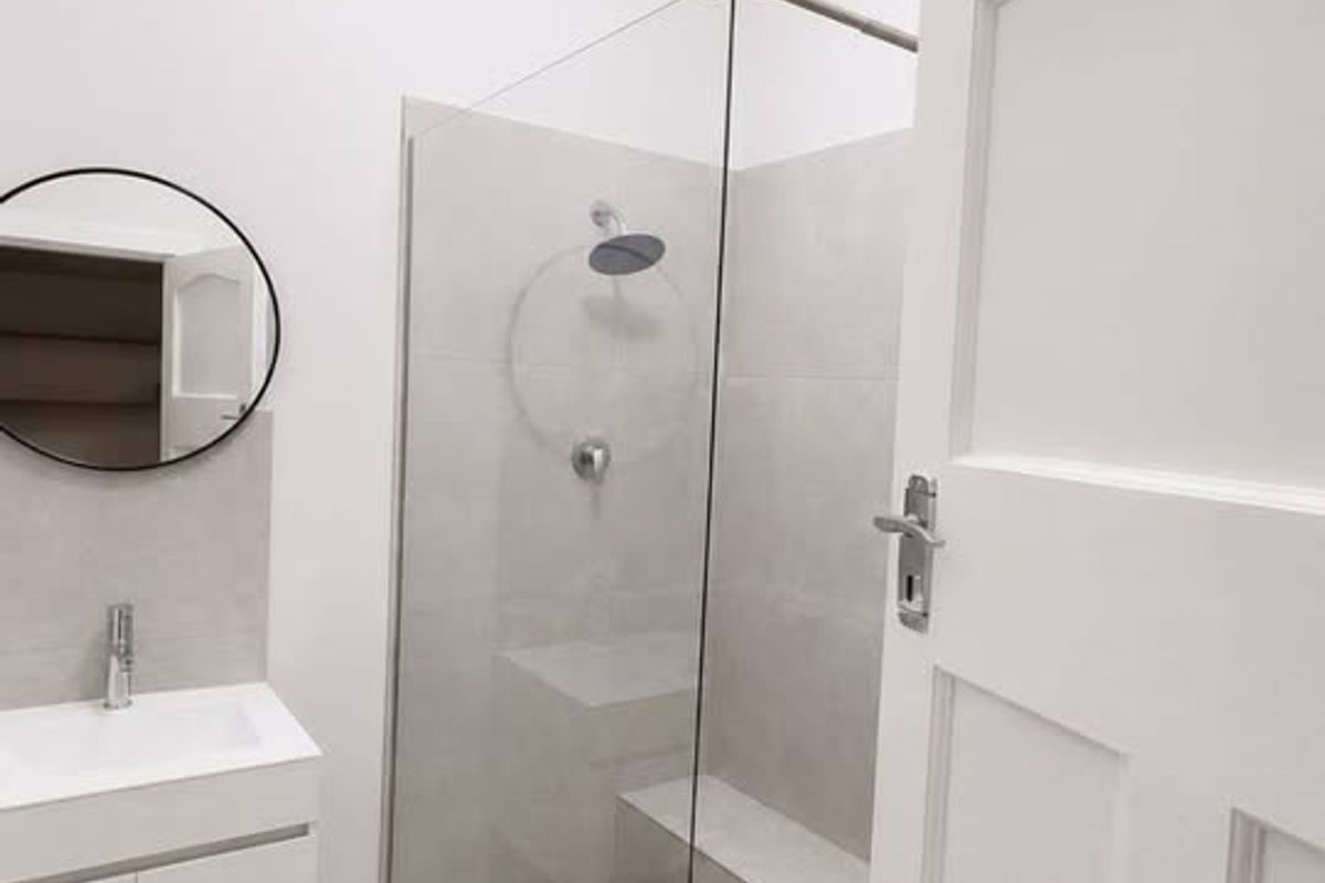 Modern bathroom featuring a walk-in shower with glass screen, wall-mounted vanity, and neutral tiling in a clean, contemporary design.
