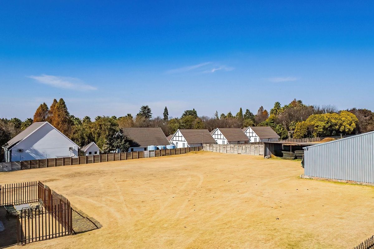 An expansive rear yard area featuring a large metal storage shed, perimeter fencing, and views of neighboring residential properties.