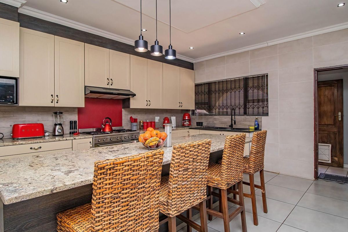 Modern kitchen featuring granite countertops, a central island with breakfast bar seating, built-in cabinetry, and a gas stove with an extractor fan.