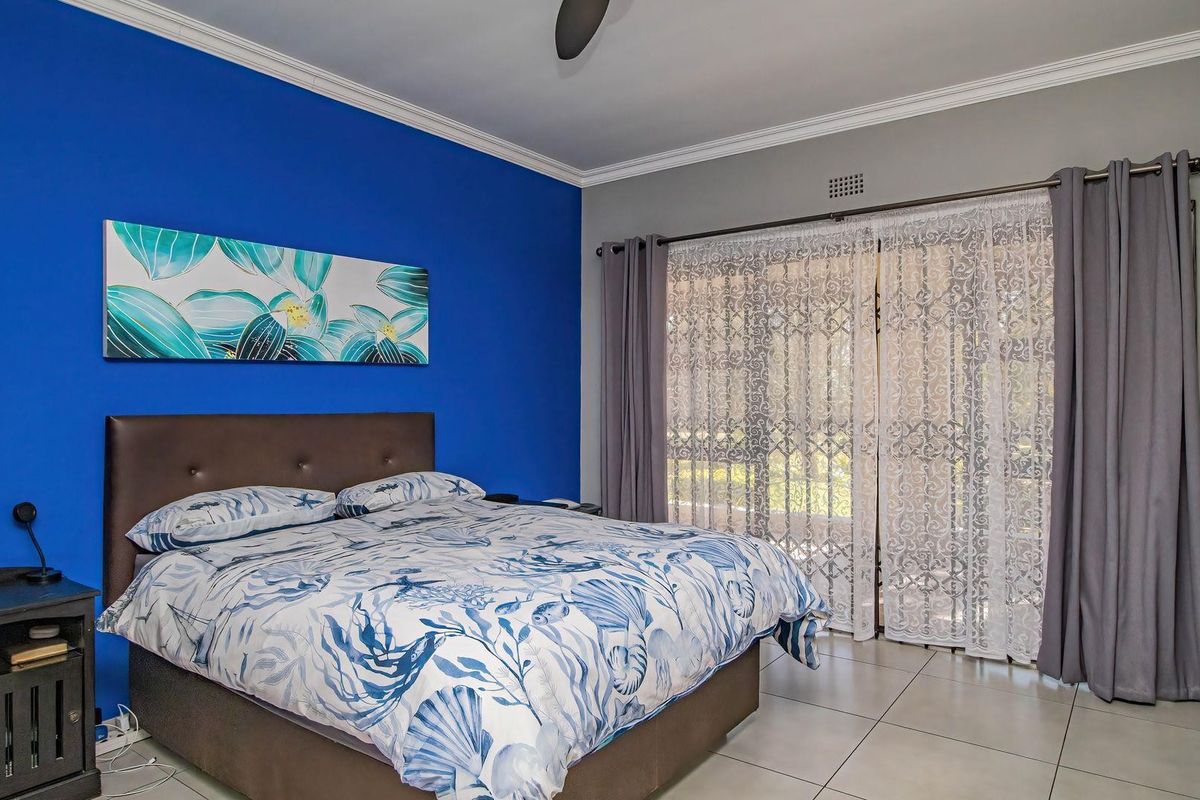 A bedroom featuring tiled flooring, a ceiling fan, and a sliding glass door with security gate providing access to the exterior.