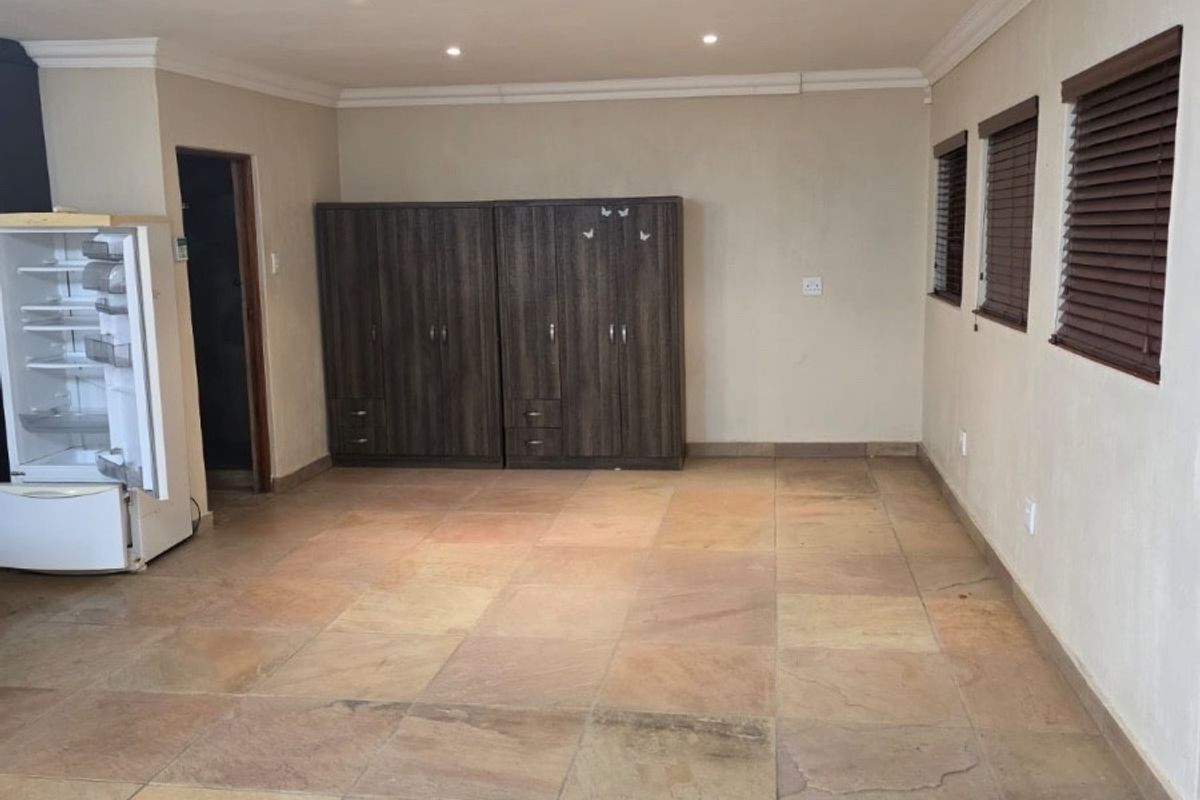 Spacious living area featuring natural stone tile flooring, recessed lighting, and venetian blinds, offering a neutral canvas for interior design.