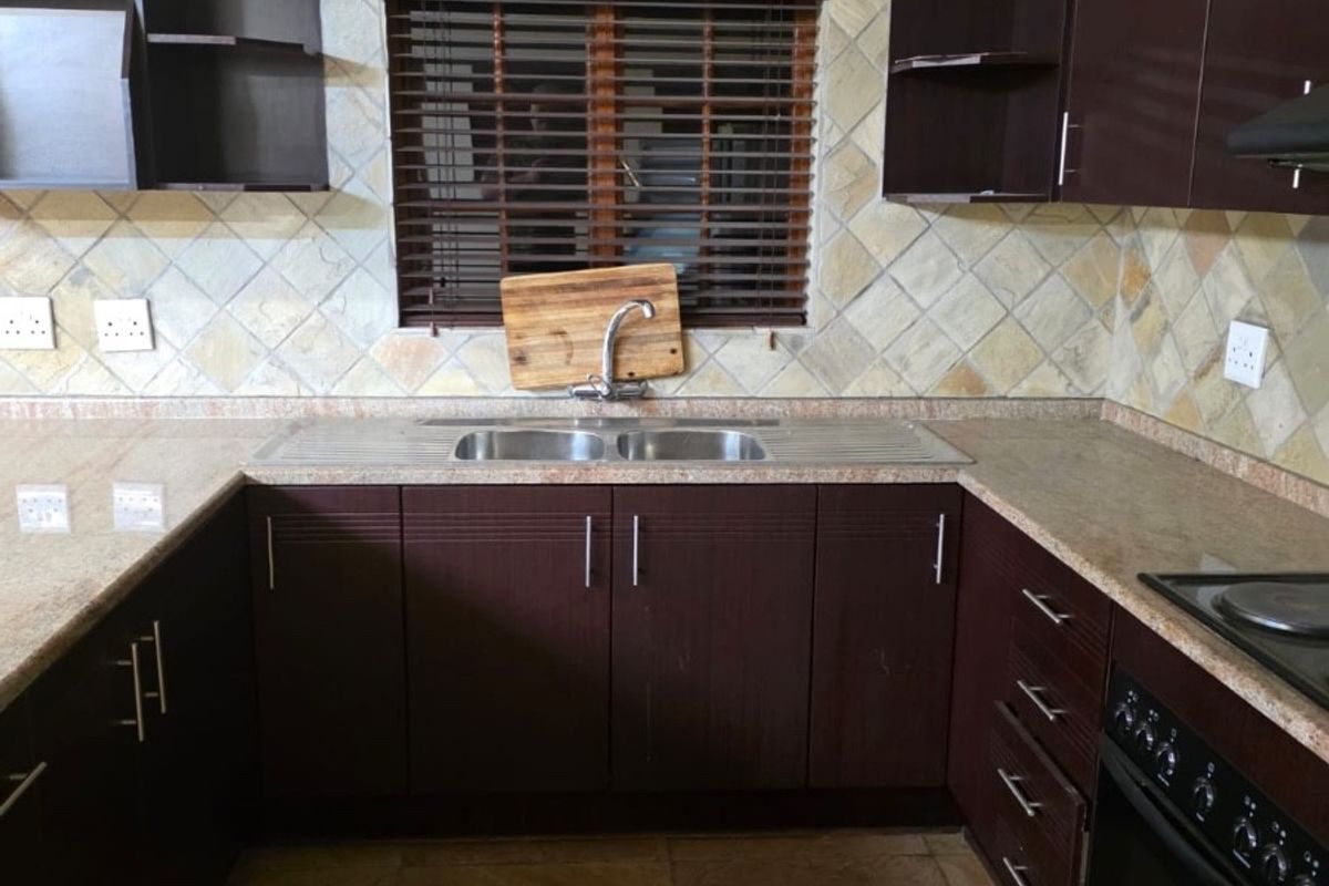 A functional kitchen featuring dark wood cabinetry, granite countertops, a double bowl sink, and a built-in oven with an electric hob.