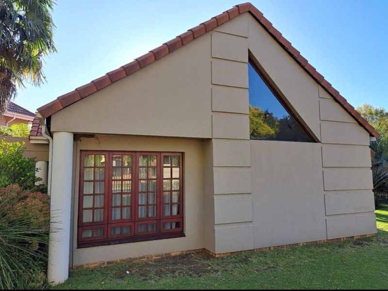 A view of the rear exterior facade featuring a distinctive triangular gable window, timber-framed windows, and a tiled roof.