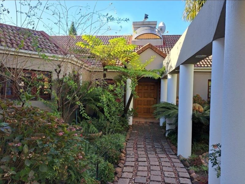 A charming front entrance featuring a brick paved walkway leading to a timber front door, sheltered by a covered porch with concrete columns.