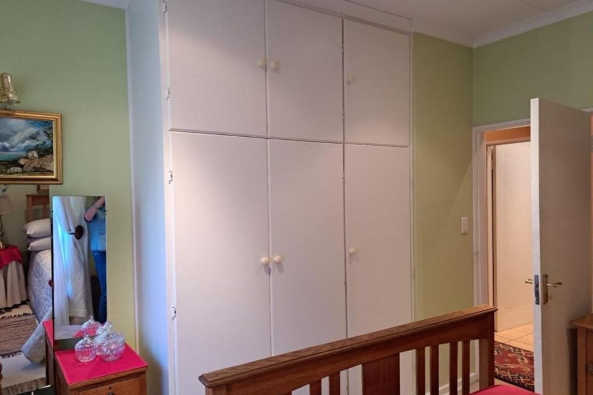 A bedroom featuring floor-to-ceiling built-in cupboards and classic coving, providing ample storage space within the room.