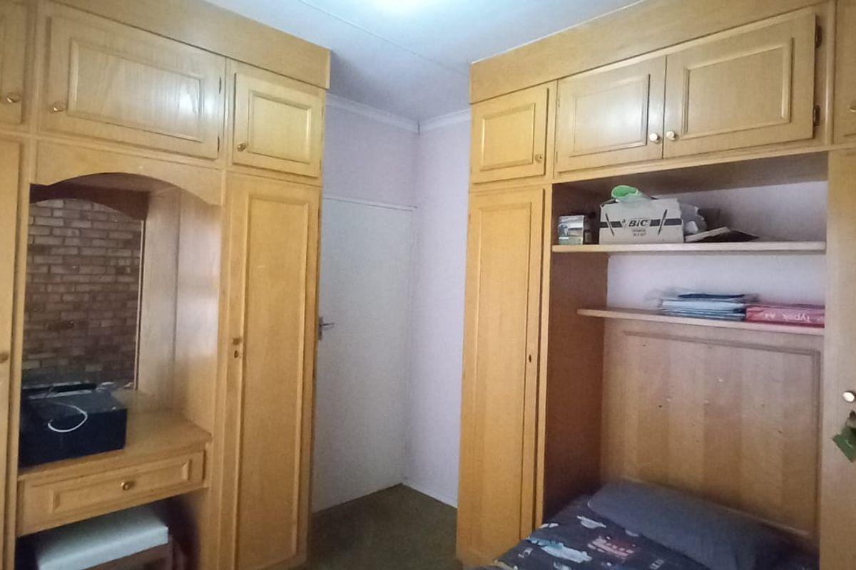 Bedroom featuring extensive built-in wooden cabinetry and a central vanity mirror, providing ample storage space.