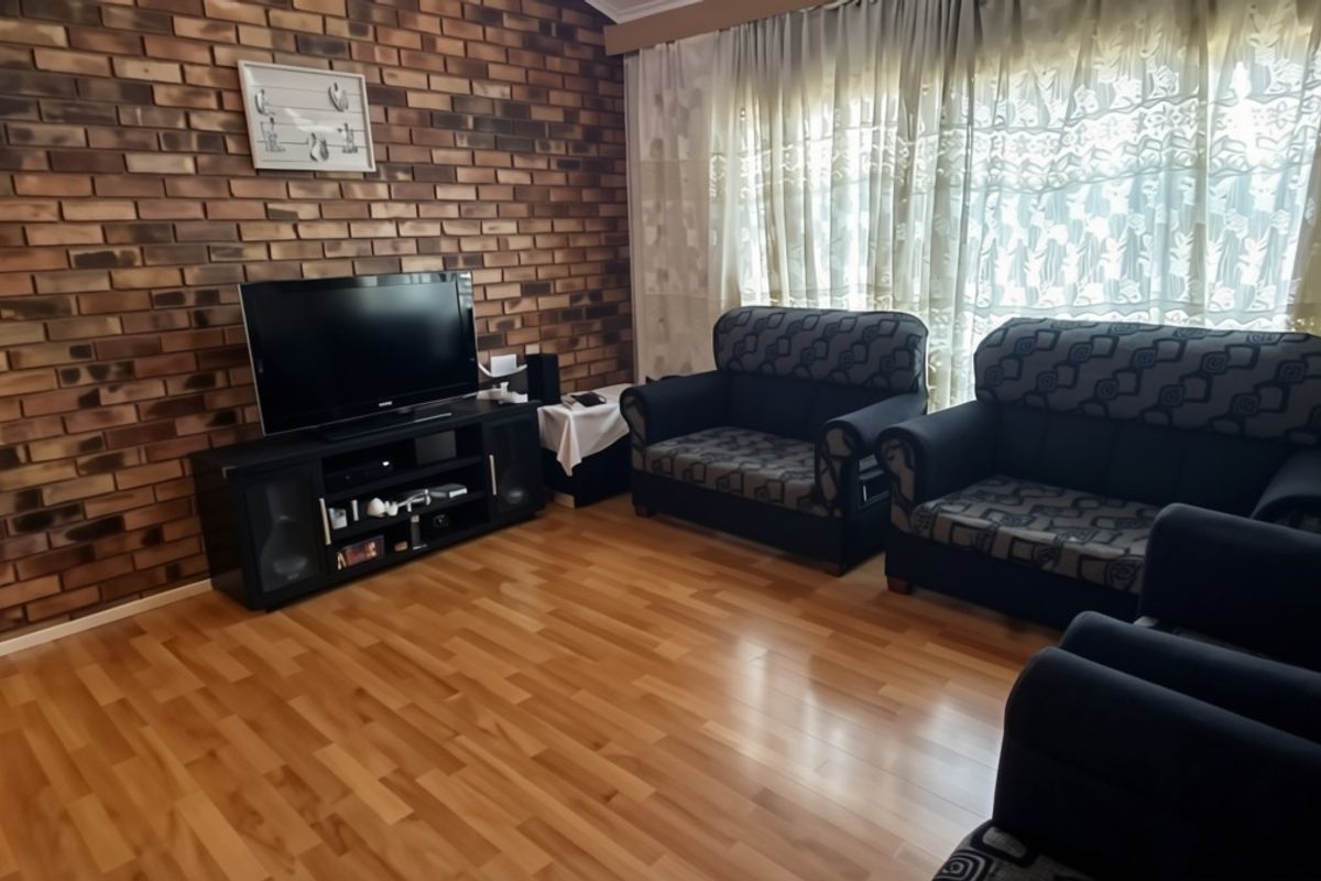 A living room featuring a prominent exposed brick feature wall and laminate flooring, offering a warm and traditional aesthetic.