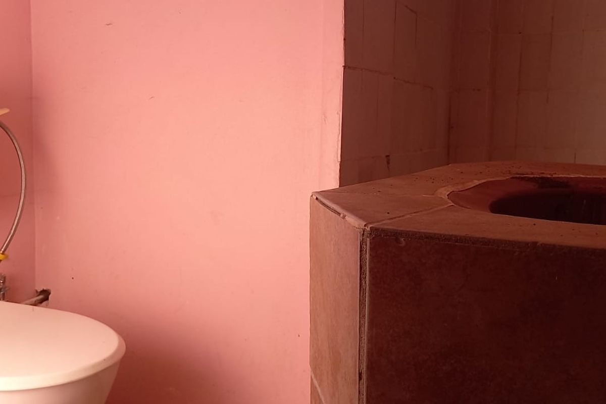 A dated bathroom featuring a standard toilet and a tiled vanity unit with a basin, requiring cosmetic updates and modernization.
