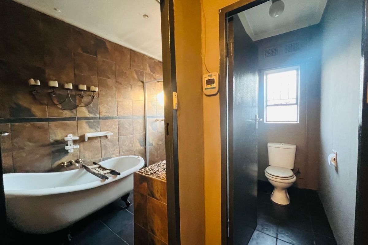 A bathroom featuring a freestanding bathtub with tiled wall finishes and a separate enclosed toilet area with tiled flooring.