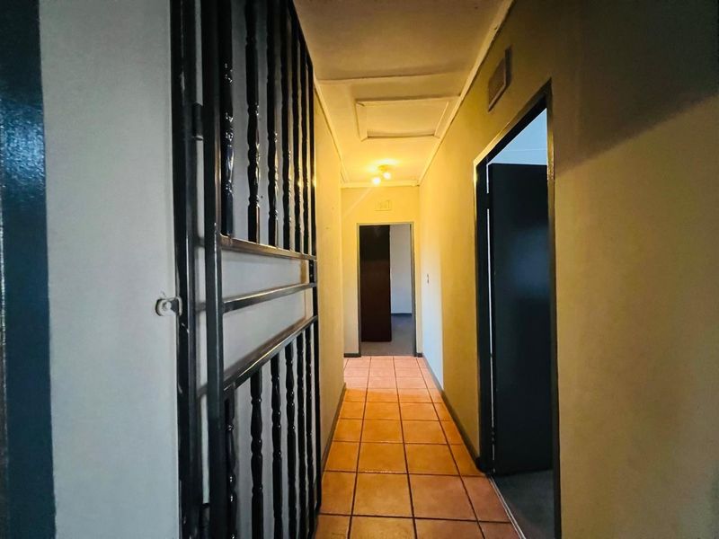 A functional hallway featuring tiled flooring and a security gate, providing access to multiple rooms within the home.