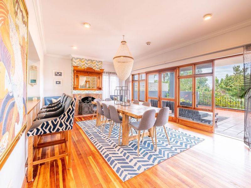 Spacious dining room featuring polished hardwood floors, a decorative fireplace, and large sliding glass doors providing seamless access to the outdoor patio area.