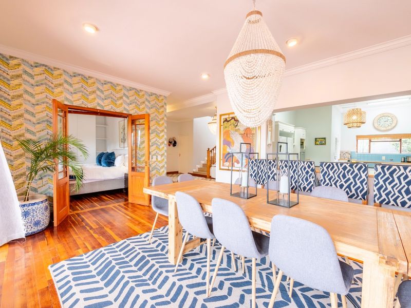 Spacious open-plan dining area featuring hardwood flooring, crown molding, and seamless flow into the adjacent kitchen and bedroom.
