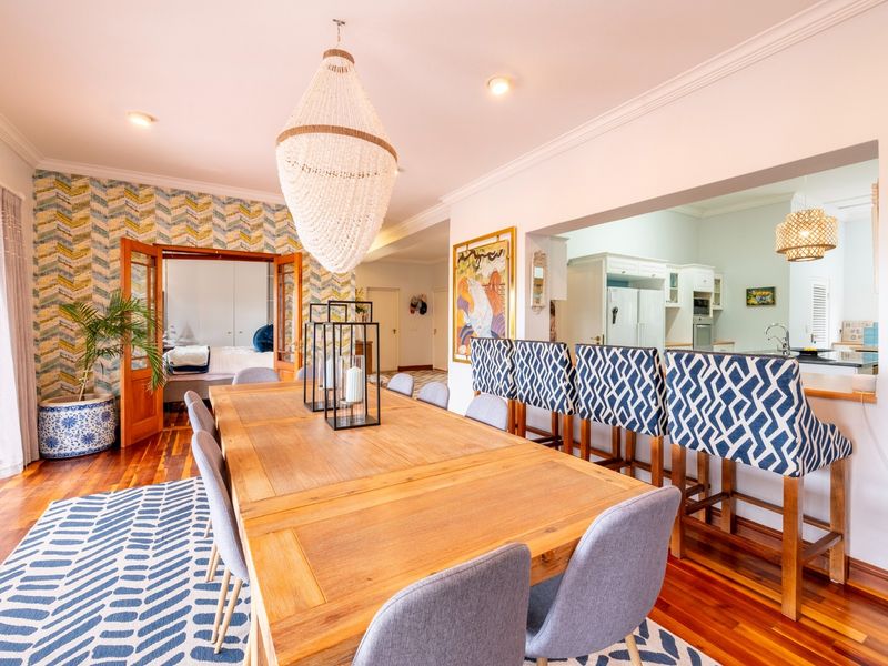 Spacious open-plan dining area featuring hardwood floors, crown molding, and a breakfast bar connecting to a well-appointed kitchen.