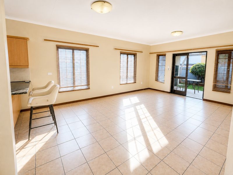 Spacious open-plan living area featuring tiled flooring, built-in kitchen cabinetry with granite countertops, and direct access to the rear patio through sliding glass doors.