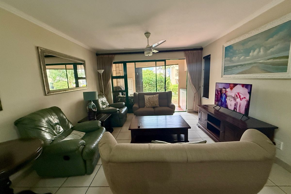 A comfortable living room featuring tiled flooring, a ceiling fan, and large sliding glass doors that provide access to an outdoor patio area.