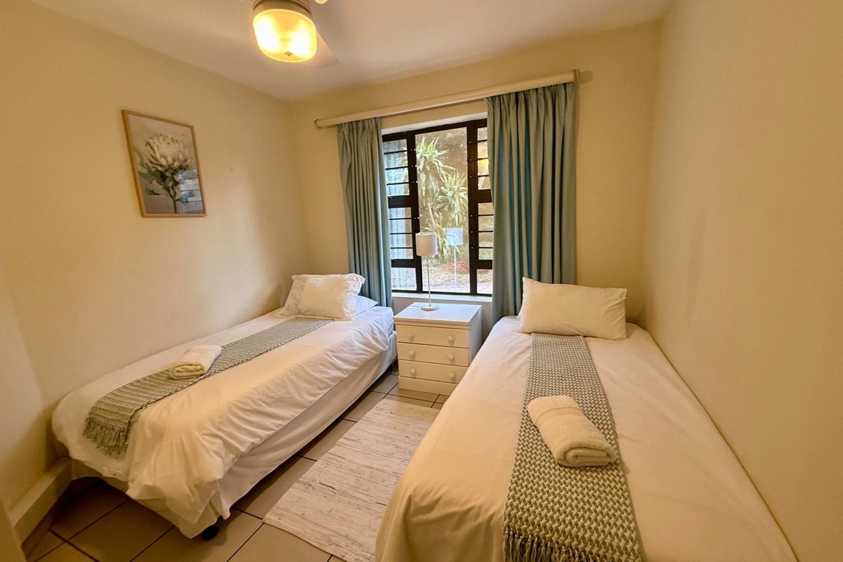 A functional bedroom featuring tiled flooring, a ceiling fan, and security bars on the window, providing a comfortable and secure sleeping space.