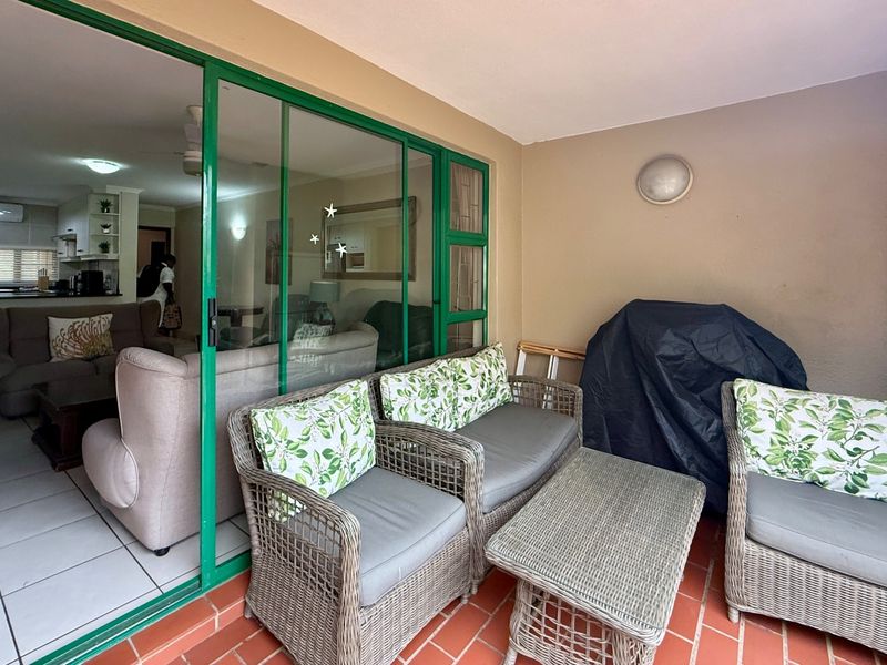 A covered patio area featuring tiled flooring, a built-in storage cupboard, and large sliding glass doors providing access to the interior living space.