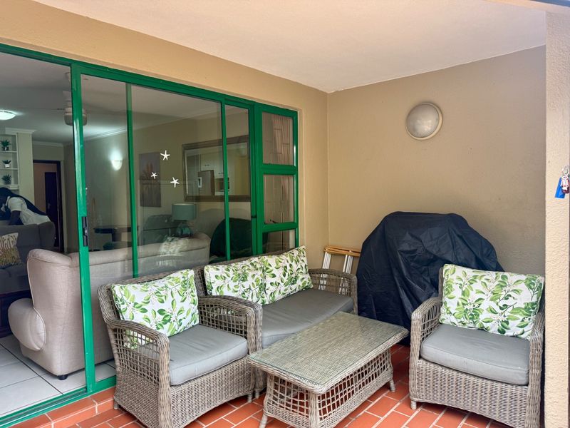 A covered patio area featuring terracotta tile flooring and a large sliding glass door providing access to the interior living space.