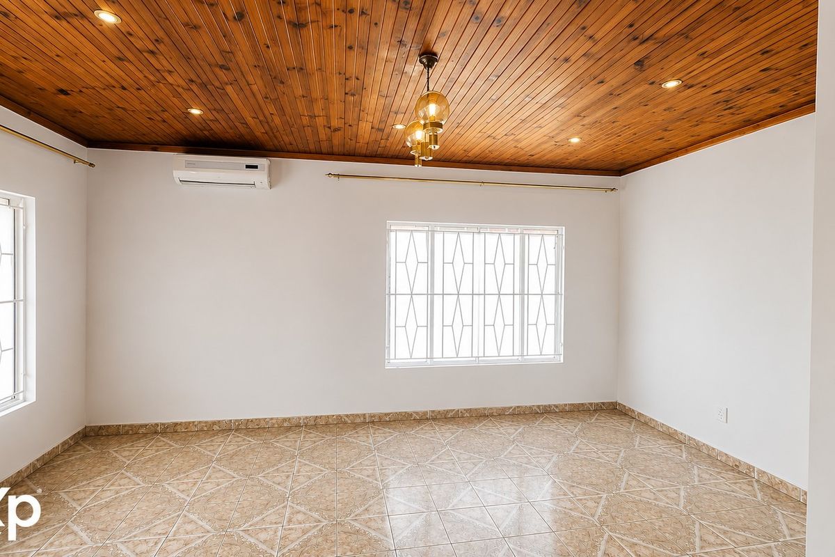 A bright, empty living area featuring a warm timber ceiling, ceramic tiled flooring, and a wall-mounted air conditioning unit.