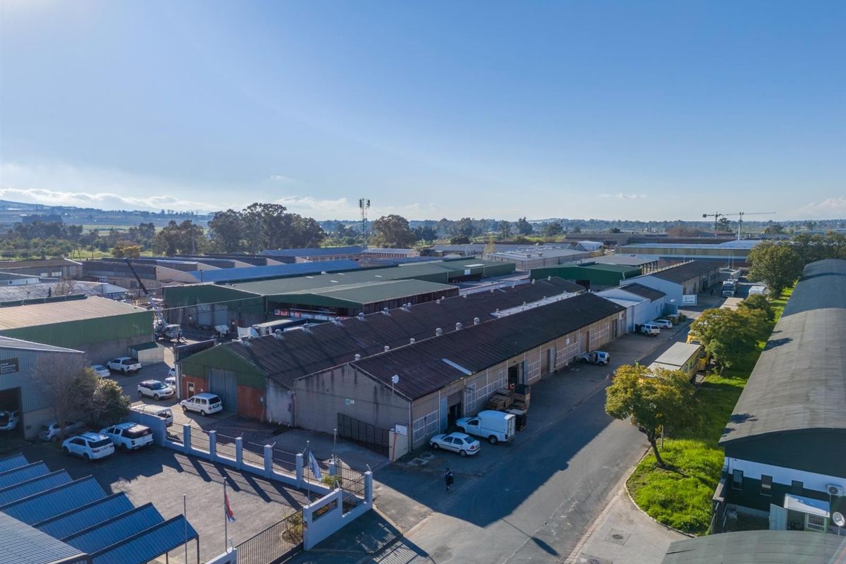 Aerial view of an industrial warehouse complex featuring multiple units, corrugated roofing, and paved access areas within a commercial estate.