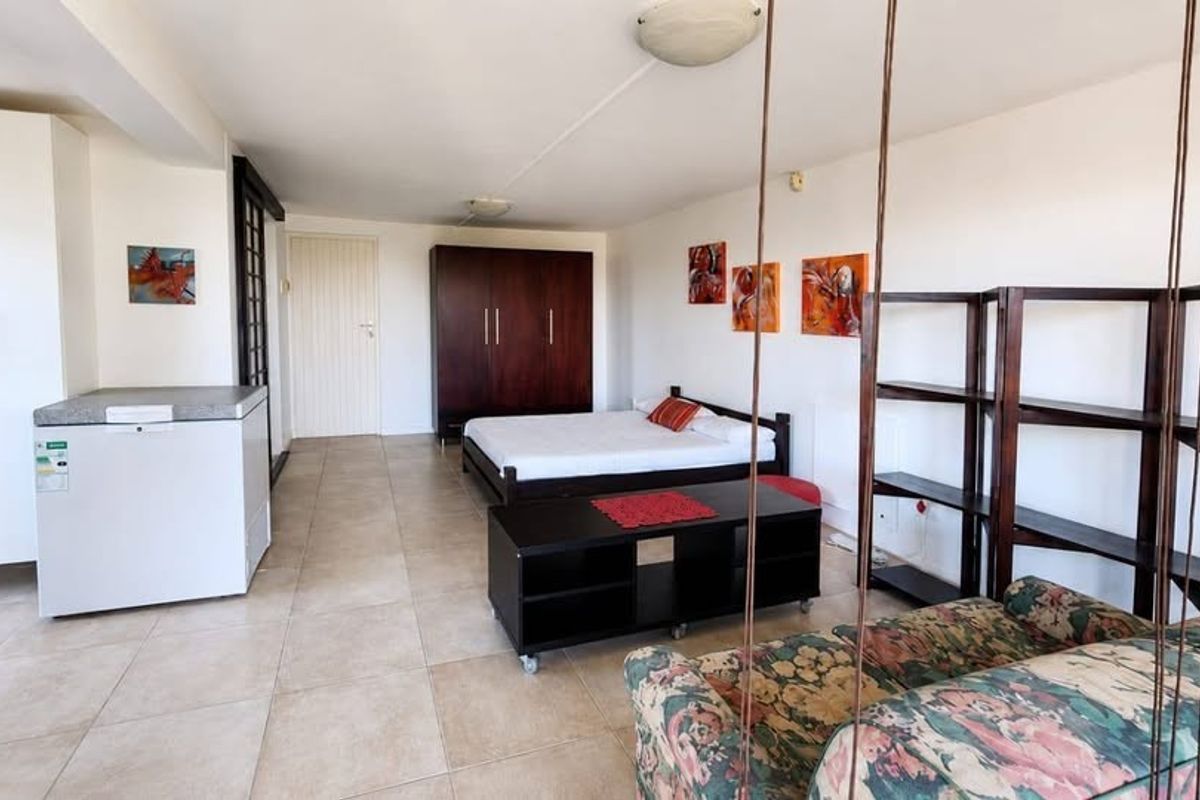 An open-plan living and sleeping area featuring neutral tiled flooring and built-in storage cabinetry.