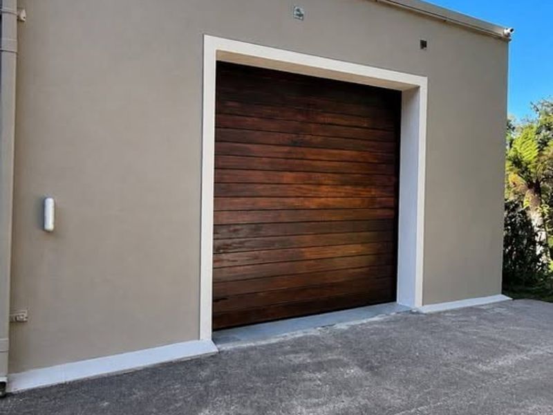 A well-maintained cottage garage featuring a modern timber sectional door and a clean concrete driveway.