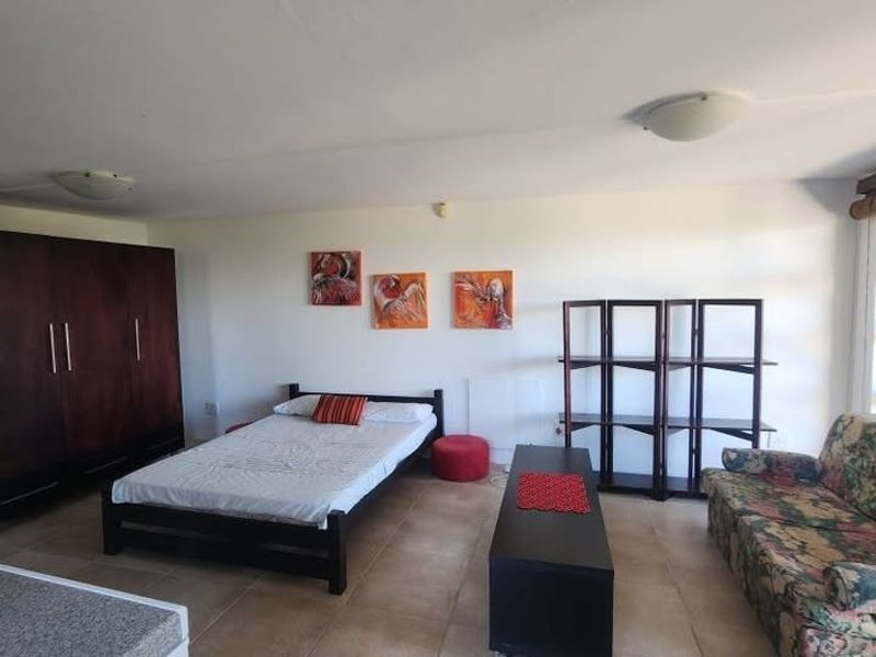 A spacious bedroom featuring tiled flooring, top-hung windows, and dual flush-mount ceiling lights, offering a functional layout with ample natural light.
