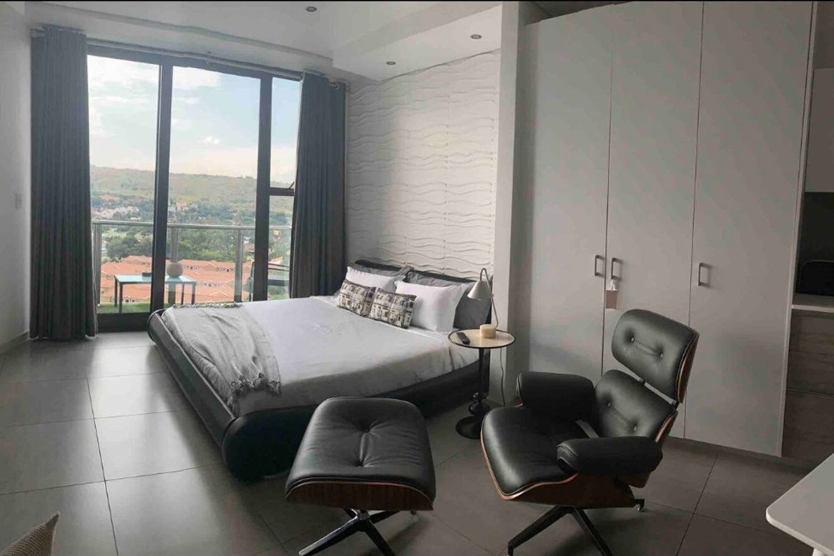 Modern bedroom featuring built-in wardrobes, large floor-to-ceiling windows with balcony access, and a textured feature wall, offering a bright and contemporary living space.