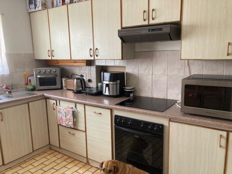 A functional kitchen featuring laminate cabinetry, tiled backsplash, built-in oven, and electric hob, offering a practical layout for daily meal preparation.