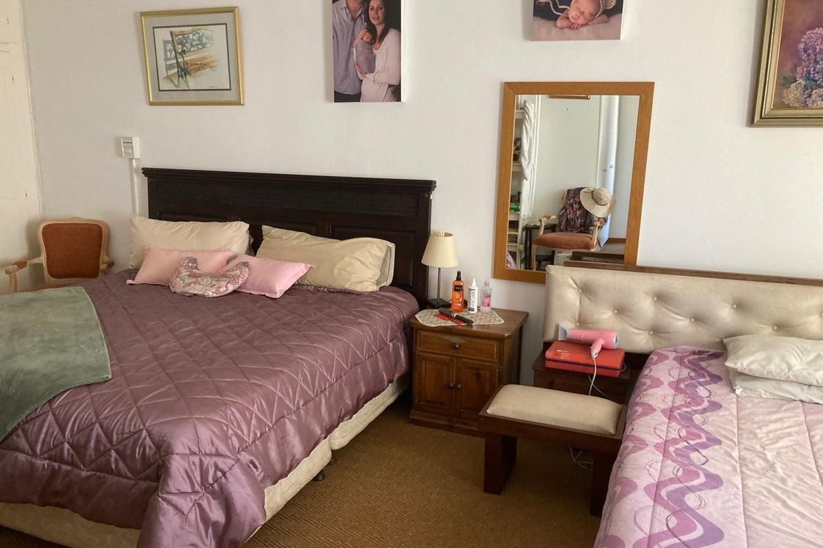 A bedroom featuring carpeted flooring and a wall-mounted mirror, providing a functional space for rest.