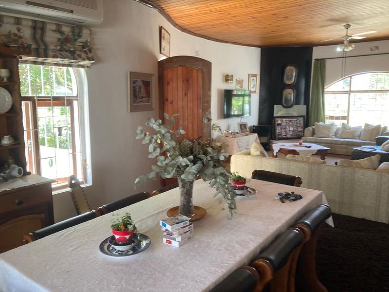 Spacious open-plan living and dining area featuring a distinctive timber ceiling, arched windows, and a fireplace, offering a warm and traditional atmosphere.