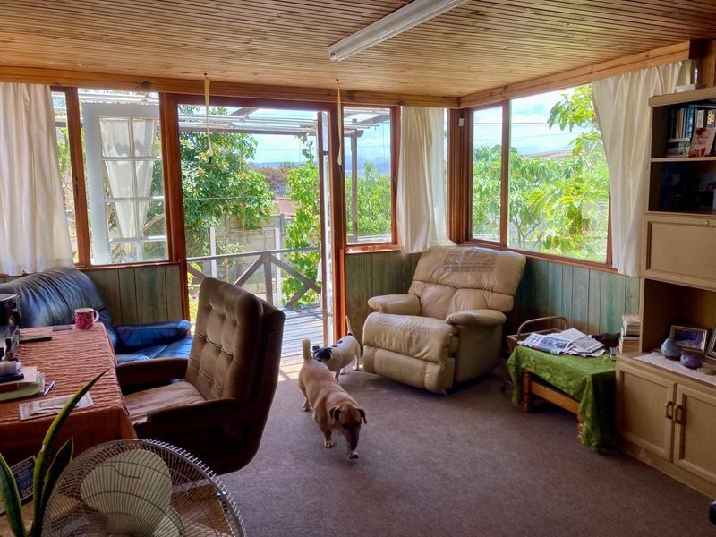Enclosed sunroom or patio area featuring timber-clad ceilings, extensive timber-framed glazing, and direct access to an outdoor deck.