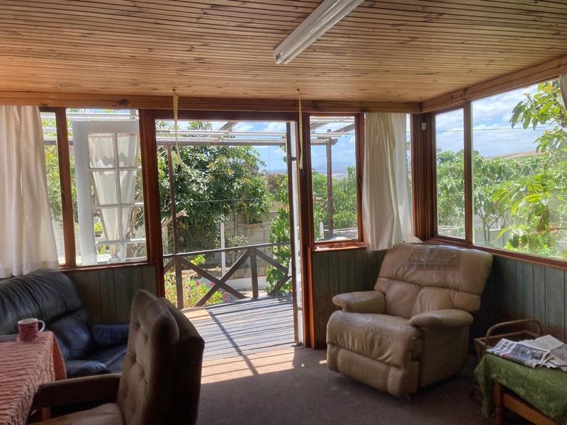 Enclosed patio area featuring timber-clad ceilings, large windows providing natural light, and direct access to the outdoor deck.