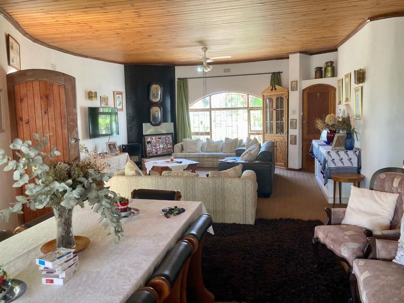 Spacious open-plan living and dining area featuring a distinctive timber ceiling, arched window, and a built-in fireplace.