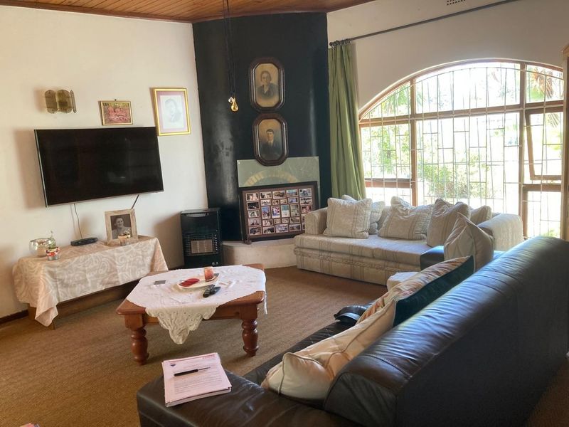 A living room featuring a large arched window with security bars, a timber ceiling, and a built-in gas fireplace.