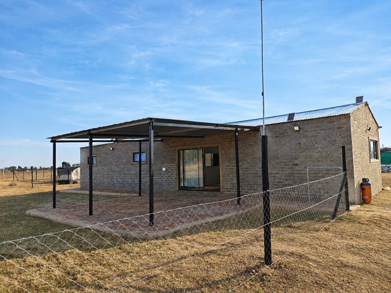 Rear view of a brick-built small holding dwelling featuring a covered patio area with paved flooring and sliding door access.