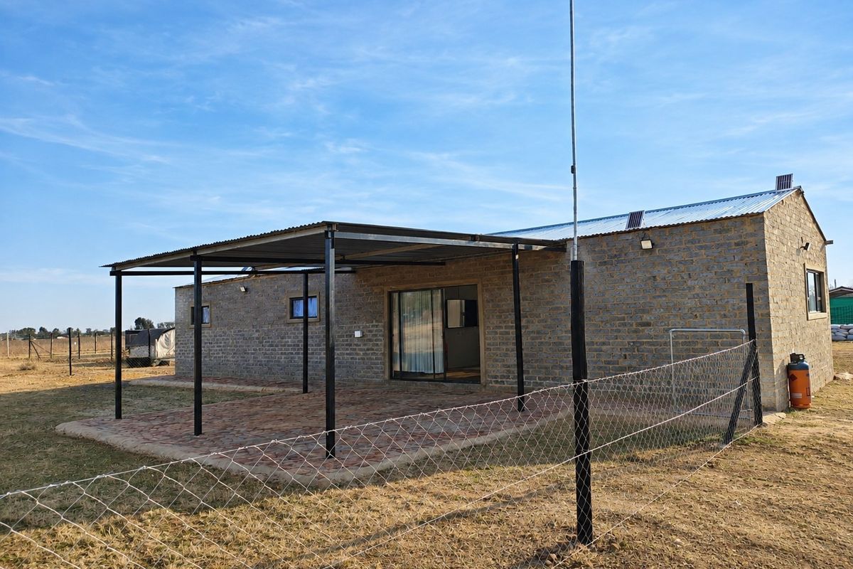 Rear view of a brick-built small holding dwelling featuring a covered patio area with paved flooring and sliding door access.