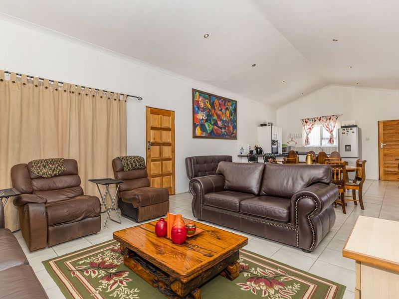 Spacious open-plan living and dining area featuring tiled floors, vaulted ceilings, and an integrated kitchen space with neutral finishes.