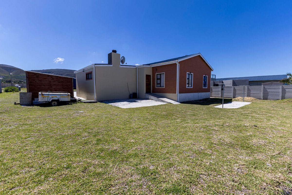 Rear view of the house featuring a concrete patio, timber shed, and a large grassed backyard enclosed by precast concrete boundary walls.