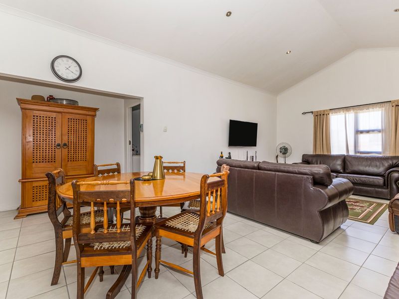 Spacious open-plan living and dining area featuring vaulted ceilings, tiled flooring, and recessed lighting, offering a versatile layout for family living.