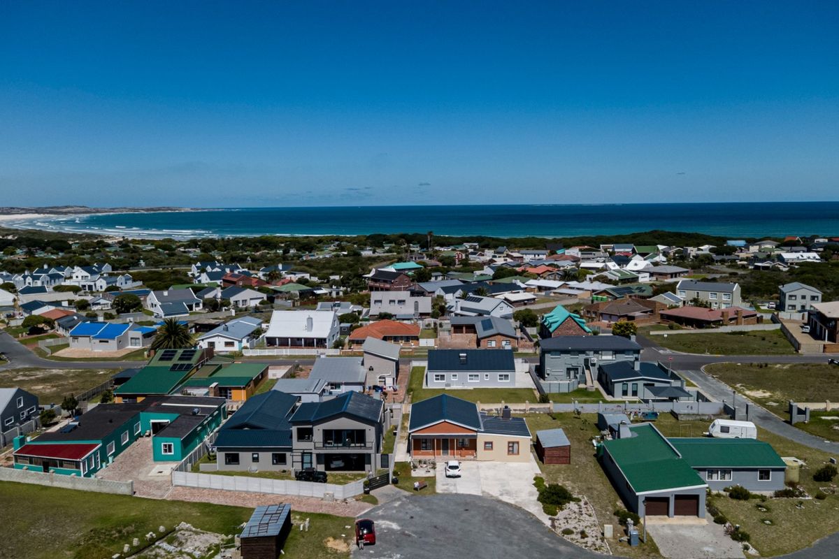 An aerial view of a coastal residential neighborhood, showcasing the property's location relative to the surrounding homes and the nearby ocean.
