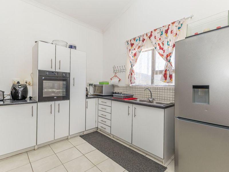 A functional kitchen featuring white cabinetry, a built-in oven, tiled backsplash, and a double sink with ample counter space.
