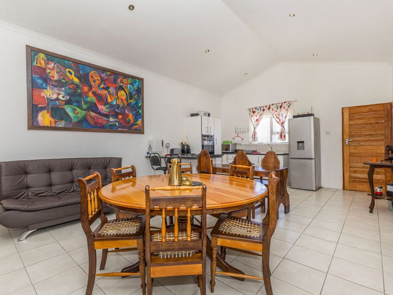 Open-plan living and dining area featuring tiled flooring, recessed lighting, and a functional kitchen space with built-in cabinetry and appliances.