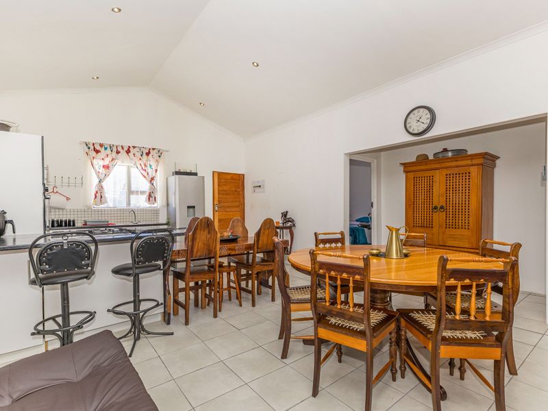 Spacious open-plan living and dining area featuring tiled flooring, a vaulted ceiling with recessed lighting, and a functional kitchen with a gas hob.