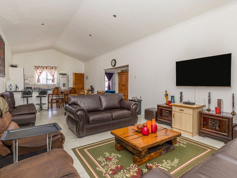 Spacious open-plan living area featuring a vaulted ceiling, tiled flooring, and an integrated kitchen with functional cabinetry and countertop space.